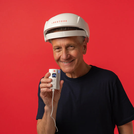 Image of a mature man wearing the Essential helmet device while holding the Rechargeable Battery Pack.
