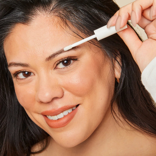Close up shot image of a woman while applying the Eyebrow Enhancing Serum.