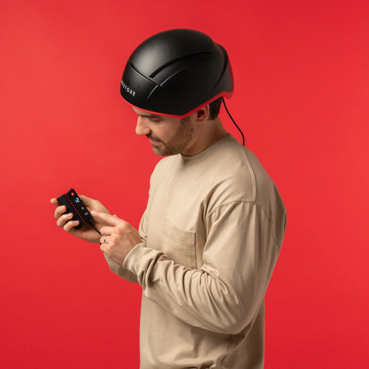 Image of a man wearing the Elite helemet device in aside view angle while holding the Elite Rechargeable Battery Pack.