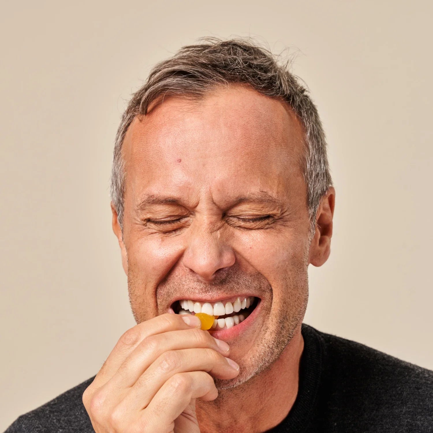 Mature man biting a biotin gummy