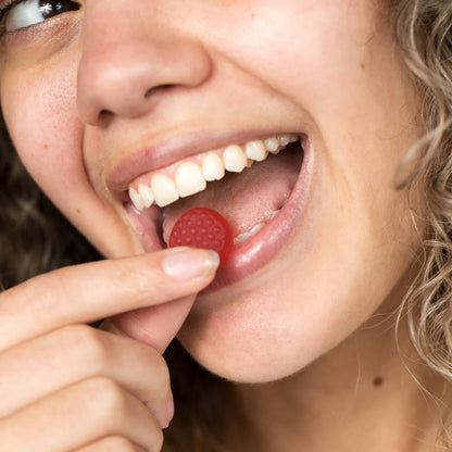 Close up shot of woman that's about to put a biotin gummy in her mouth.