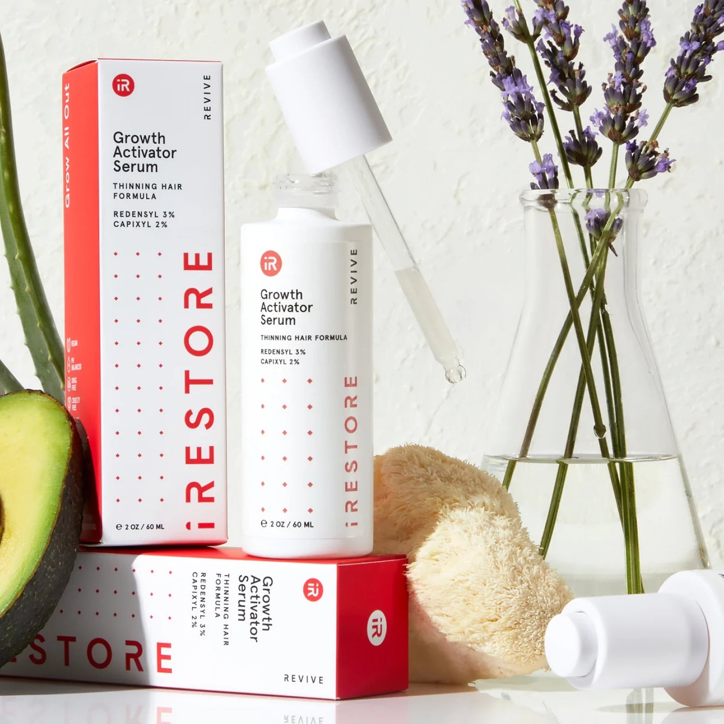 Growth activator serum bottle, dropper, and packaging, with fruits behind 