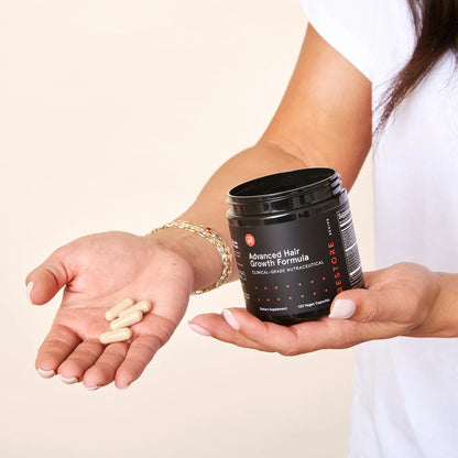 Image of a woman's hand showing the tablets of the Advanced Hair Growth Formula on her palm while on the other hand holding the jar.