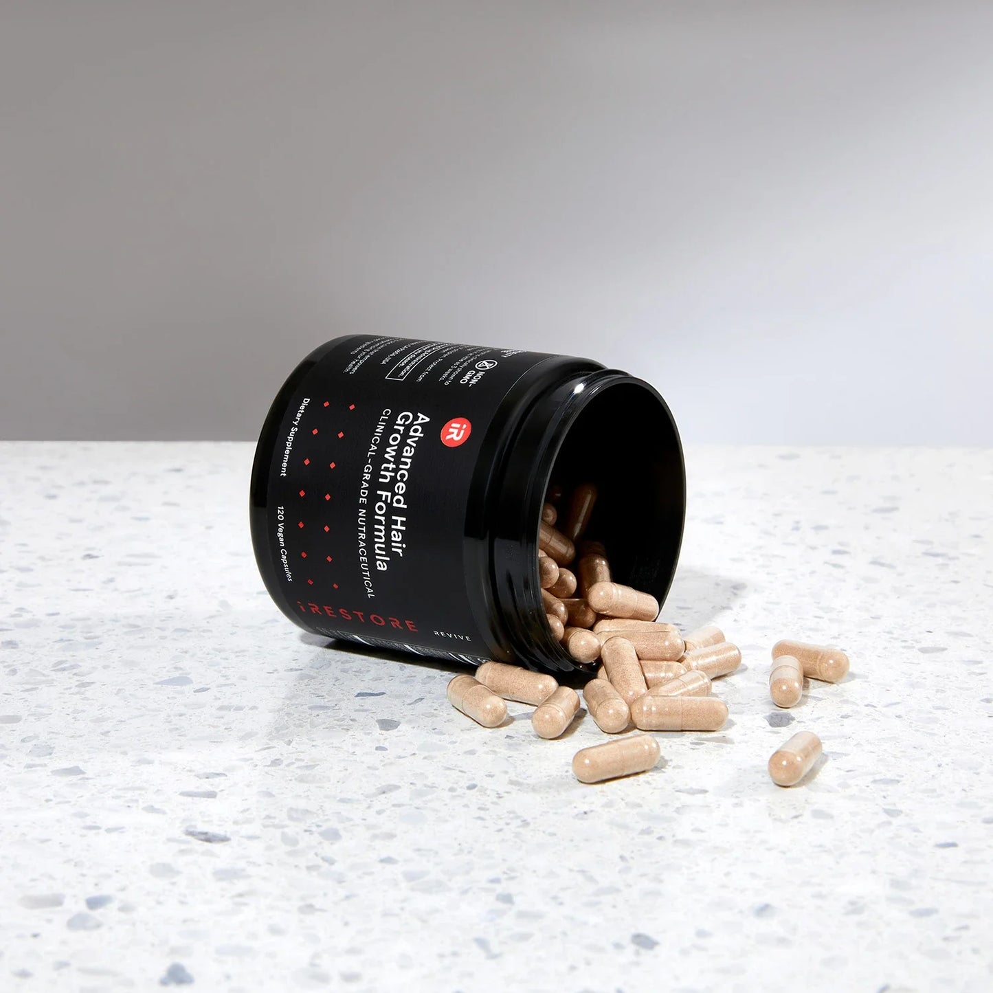 Image showing an opened jar of the Advanced Hair Growth Formula tipped on its side, placed on a table with spilled tablets around it.