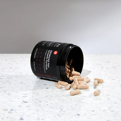 Image showing an opened jar of the Advanced Hair Growth Formula tipped on its side, placed on a table with spilled tablets around it.