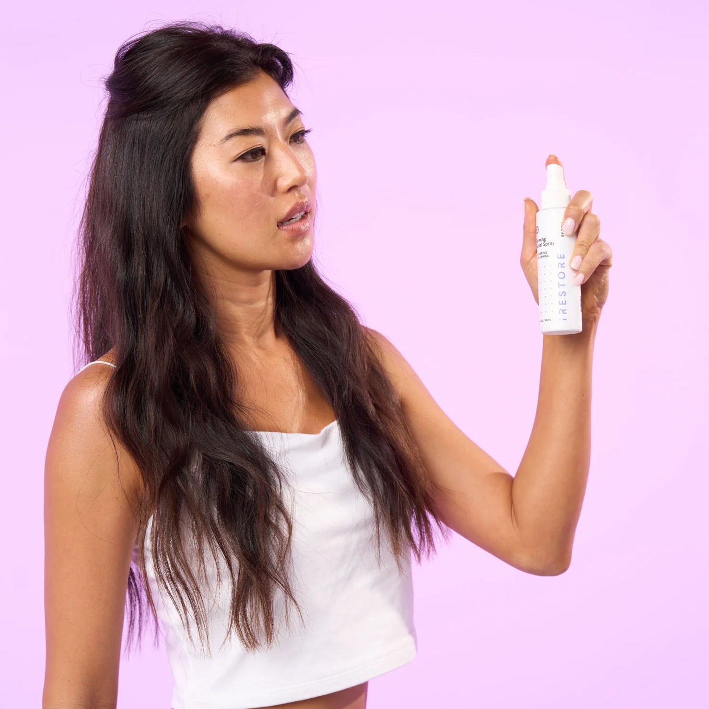 Woman spraying calming facial spray away from her face