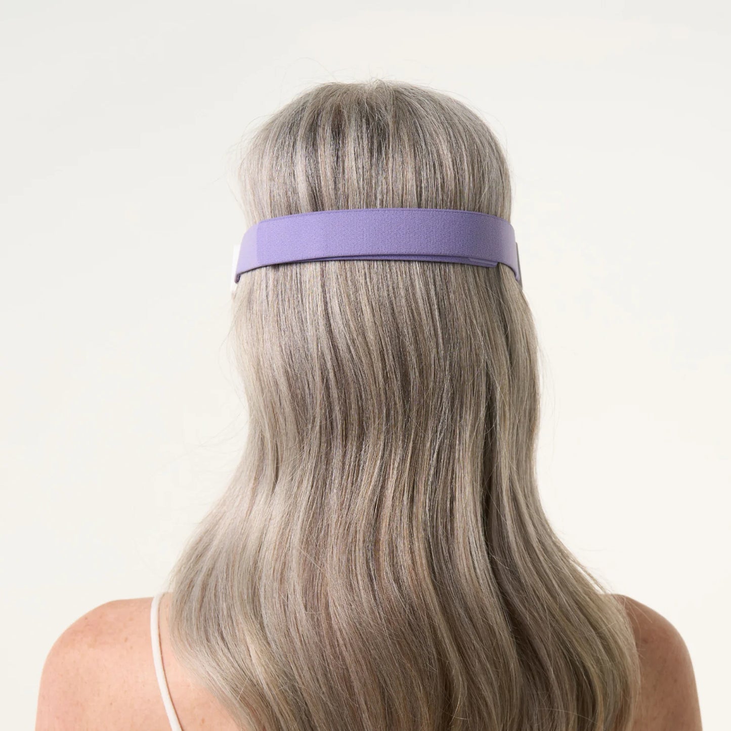 back shot of a woman wearing the LED eye mask where the strap can be seen.