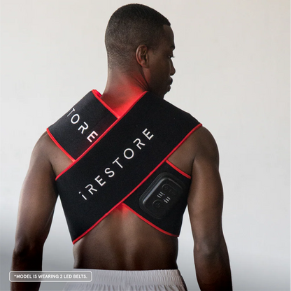 Man wearing a black and red 'iRestore' LED belt on a plain background